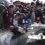 Palestinians stand in wait for a food portion at a distribution centre south of Khan Yunis in the southern Gaza Strip on December 17, 2024