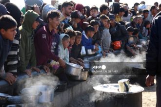 Palestinians stand in wait for a food portion at a distribution centre south of Khan Yunis in the southern Gaza Strip on December 17, 2024